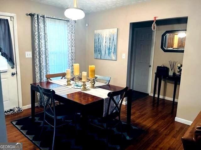 dining space with dark hardwood / wood-style flooring, a textured ceiling, and plenty of natural light