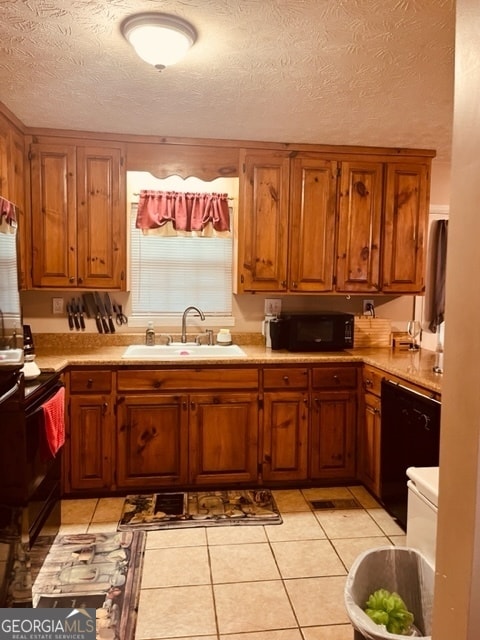 kitchen featuring black appliances, light tile patterned floors, sink, and a textured ceiling