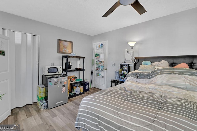 bedroom featuring stainless steel fridge, ceiling fan, and light hardwood / wood-style flooring