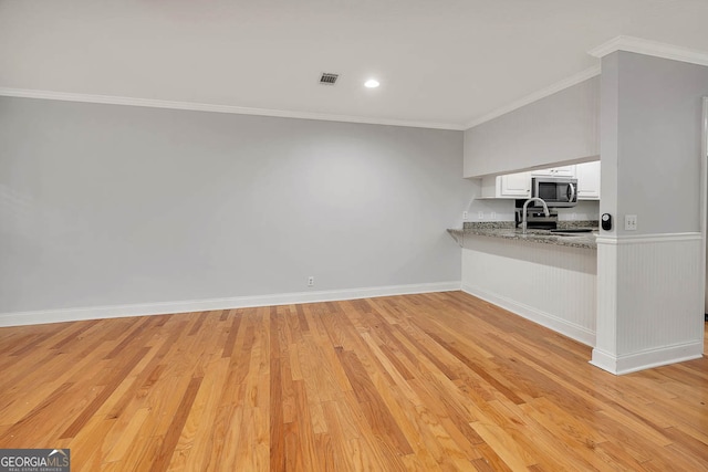 kitchen featuring crown molding, light stone countertops, appliances with stainless steel finishes, light hardwood / wood-style floors, and white cabinetry