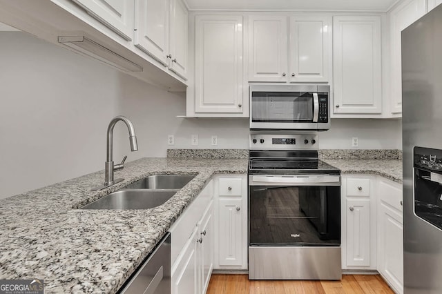 kitchen with sink, white cabinetry, stainless steel appliances, and light hardwood / wood-style flooring