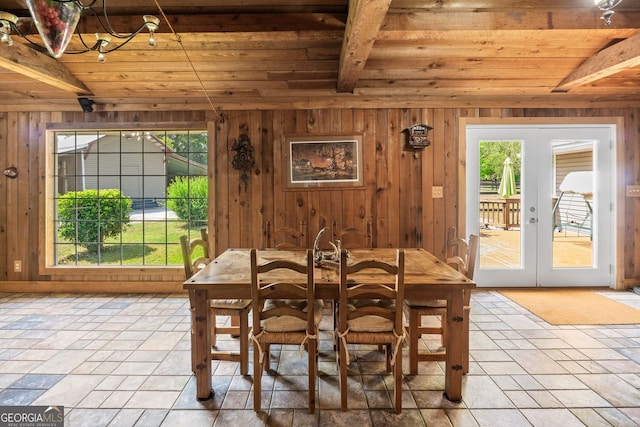 dining space with french doors, wooden walls, and a healthy amount of sunlight