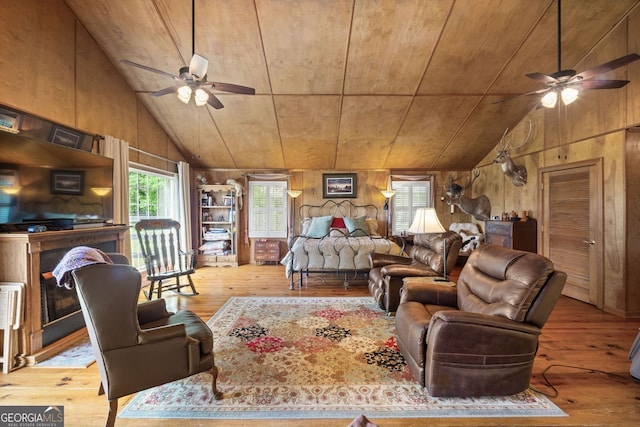 living room with ceiling fan, wood walls, and light hardwood / wood-style floors