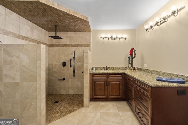 bathroom featuring tile patterned flooring, vanity, and a tile shower