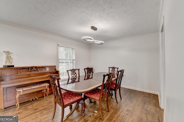 dining room with hardwood / wood-style floors, a textured ceiling, and ornamental molding