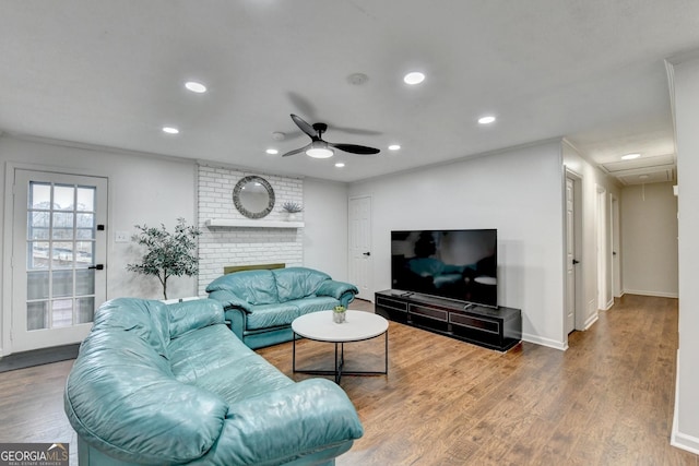 living room featuring a fireplace, hardwood / wood-style floors, ceiling fan, and ornamental molding