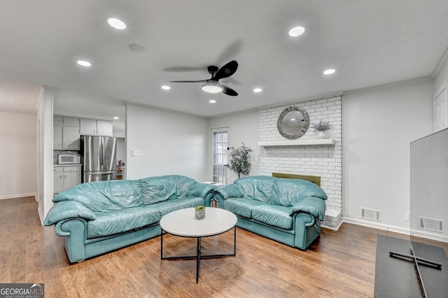 living room with a fireplace, hardwood / wood-style flooring, and ceiling fan