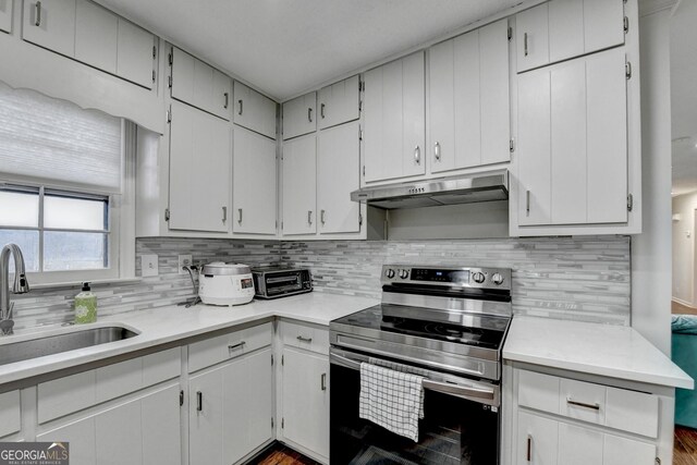 kitchen featuring stainless steel electric stove, white cabinets, sink, and tasteful backsplash