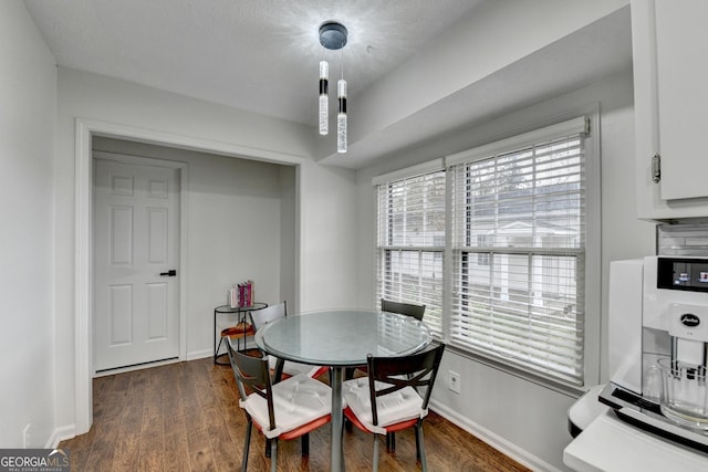 dining area with a textured ceiling and dark wood-type flooring