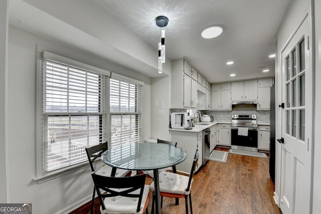 kitchen with tasteful backsplash, dark wood-type flooring, white cabinets, and stainless steel appliances