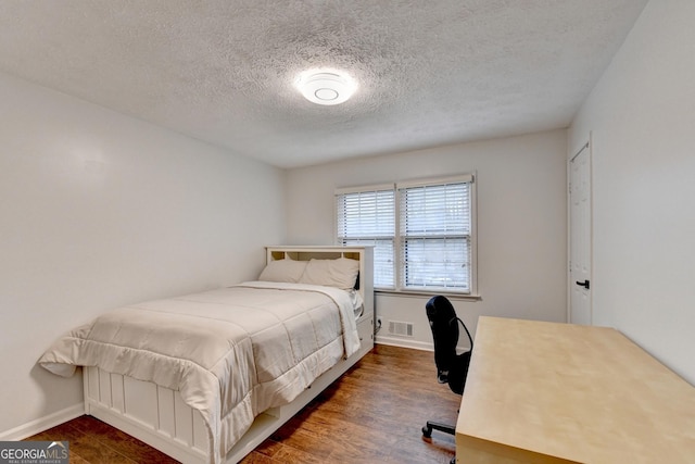 bedroom with dark hardwood / wood-style flooring and a textured ceiling