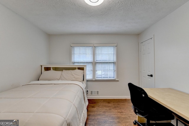 bedroom with a textured ceiling and dark wood-type flooring