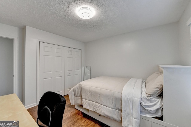 bedroom with a closet, a textured ceiling, and hardwood / wood-style flooring