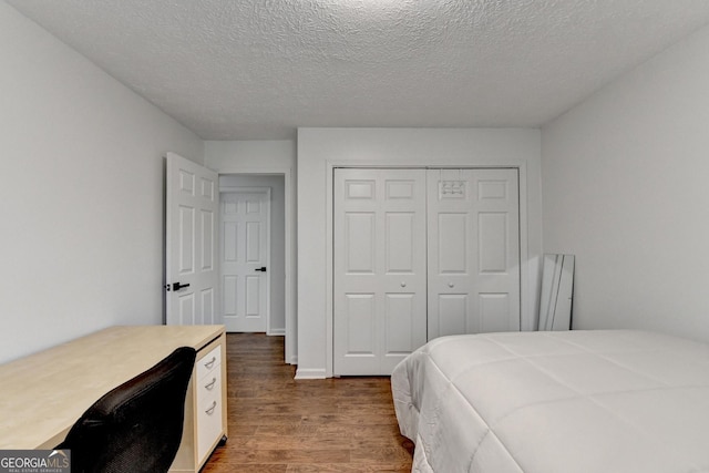 bedroom featuring a textured ceiling, dark wood-type flooring, and a closet