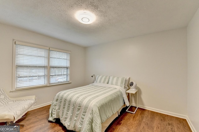 bedroom with a textured ceiling and hardwood / wood-style flooring