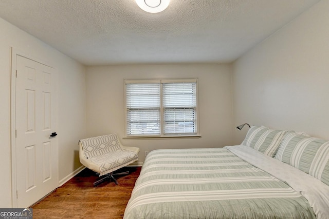 bedroom with a textured ceiling and hardwood / wood-style flooring