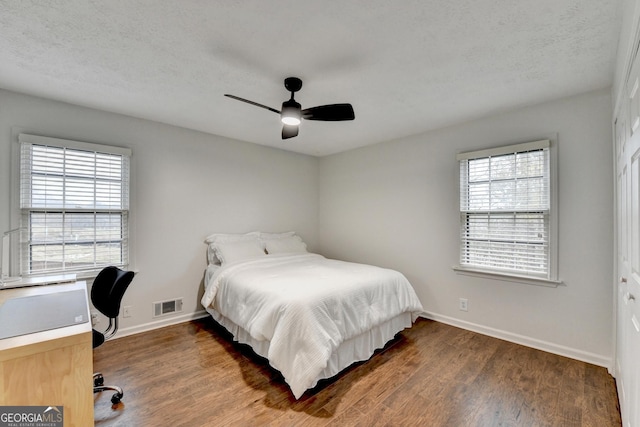 bedroom featuring multiple windows, ceiling fan, and dark hardwood / wood-style flooring