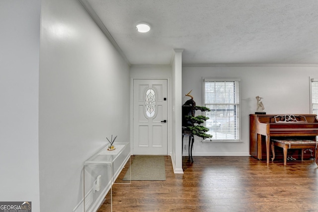 foyer with dark wood-type flooring, a textured ceiling, and ornamental molding