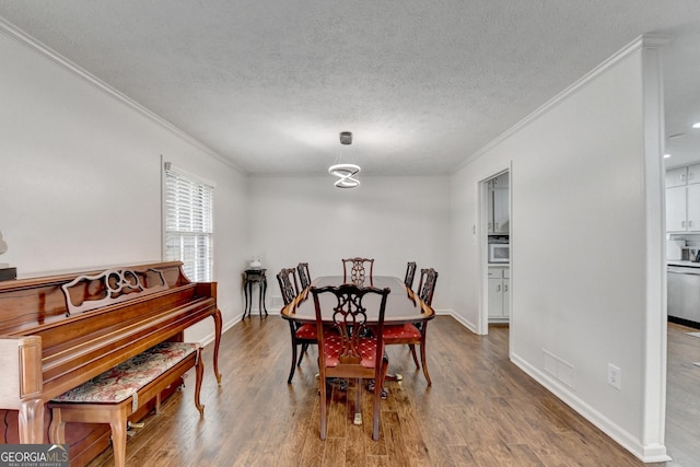 dining area with wood-type flooring, a textured ceiling, and ornamental molding