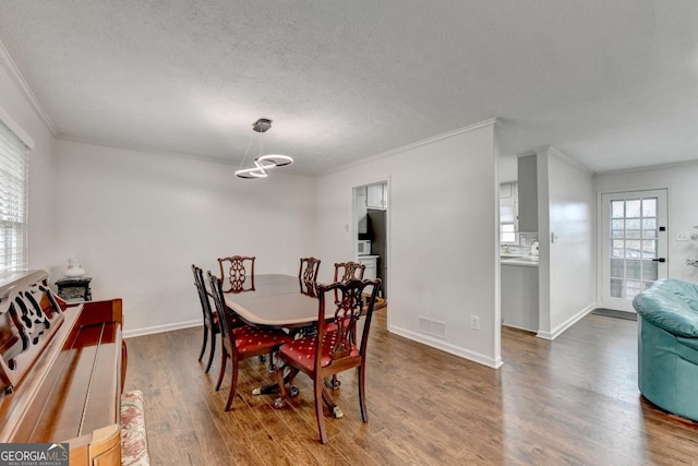 dining area featuring hardwood / wood-style flooring, crown molding, and a textured ceiling