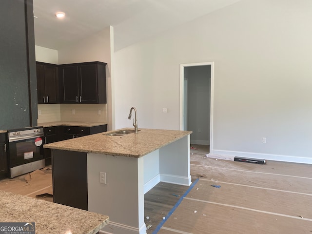 kitchen featuring a center island with sink, stainless steel range oven, sink, and hardwood / wood-style floors