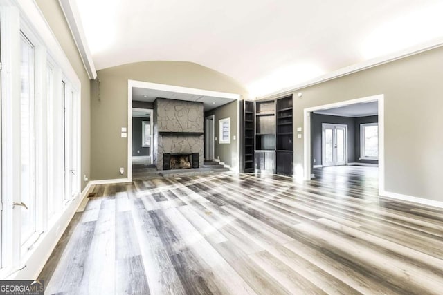 unfurnished living room with hardwood / wood-style floors, a stone fireplace, and vaulted ceiling