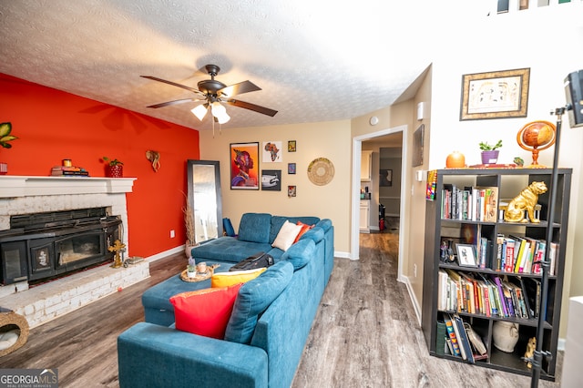 living room with a fireplace, ceiling fan, hardwood / wood-style floors, and a textured ceiling