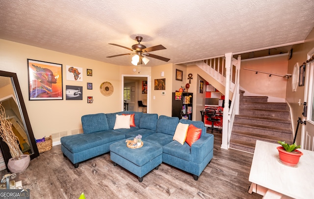 living room featuring ceiling fan, wood-type flooring, and a textured ceiling