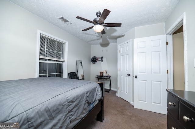 carpeted bedroom with ceiling fan and a textured ceiling