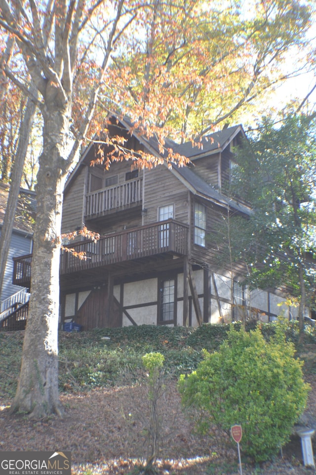 rear view of property with a wooden deck and a balcony