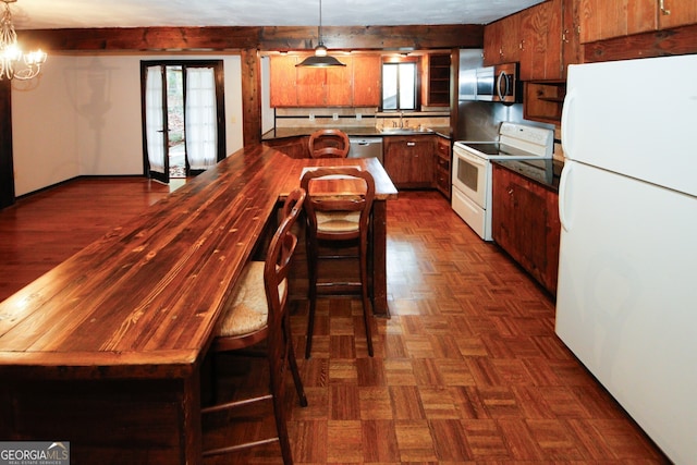 kitchen with dark parquet flooring, stainless steel appliances, sink, pendant lighting, and a chandelier