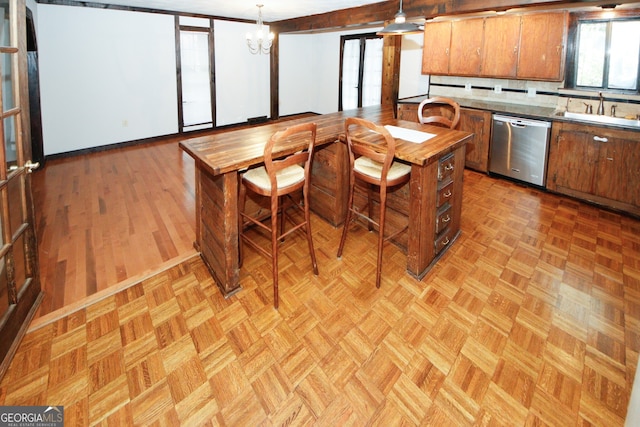 kitchen with hanging light fixtures, light parquet flooring, stainless steel dishwasher, and sink