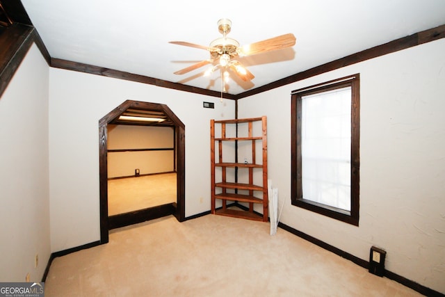 unfurnished bedroom featuring ceiling fan, light colored carpet, and crown molding