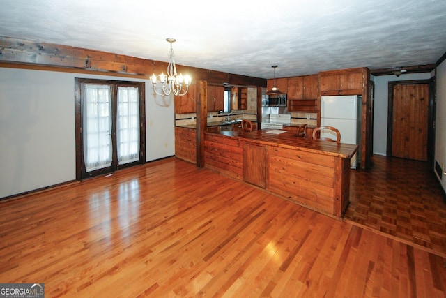 kitchen with kitchen peninsula, pendant lighting, white appliances, and light wood-type flooring