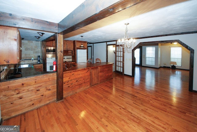 kitchen with hanging light fixtures, an inviting chandelier, beamed ceiling, white refrigerator, and hardwood / wood-style floors