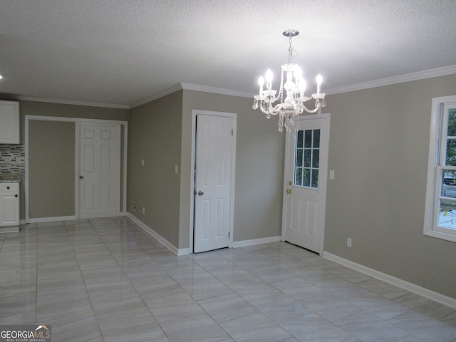 unfurnished dining area with crown molding, a textured ceiling, and an inviting chandelier