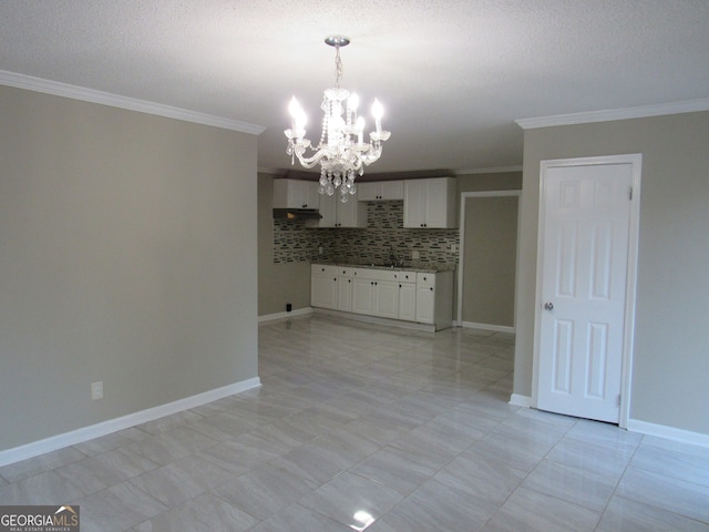 kitchen featuring backsplash, crown molding, an inviting chandelier, white cabinetry, and hanging light fixtures