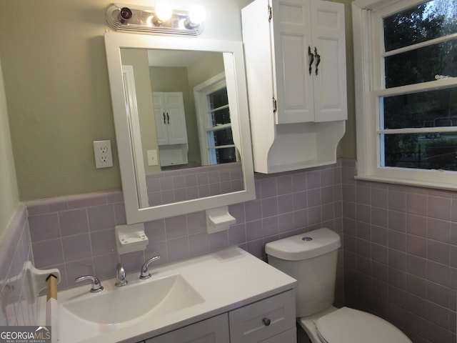 bathroom featuring vanity, toilet, and tile walls