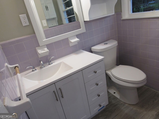 bathroom featuring hardwood / wood-style floors, vanity, tile walls, and toilet