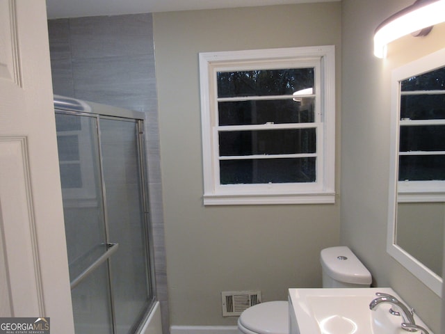 full bathroom featuring combined bath / shower with glass door, toilet, and sink