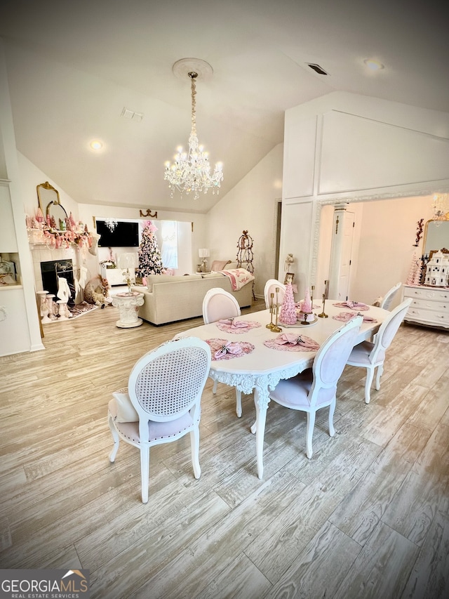 dining area featuring a chandelier, light hardwood / wood-style flooring, and vaulted ceiling