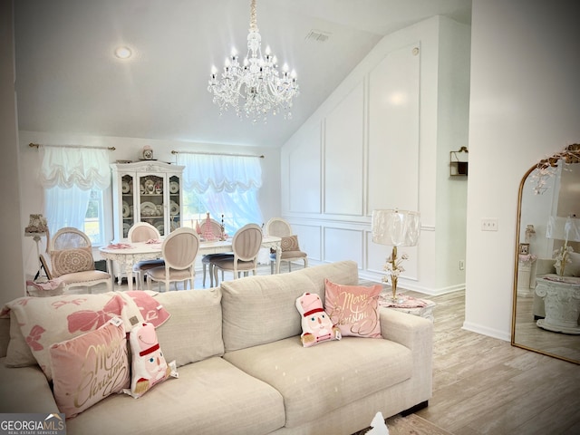 living room featuring light wood-type flooring, lofted ceiling, and an inviting chandelier