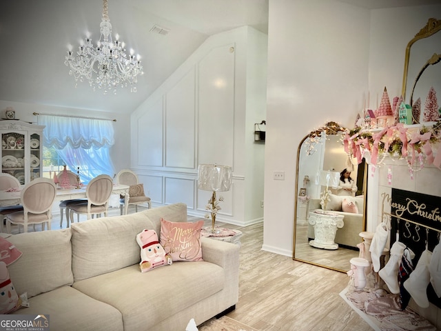 living room featuring light hardwood / wood-style flooring, vaulted ceiling, and an inviting chandelier