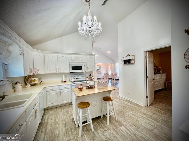 kitchen with white appliances, sink, white cabinets, light hardwood / wood-style floors, and a kitchen island