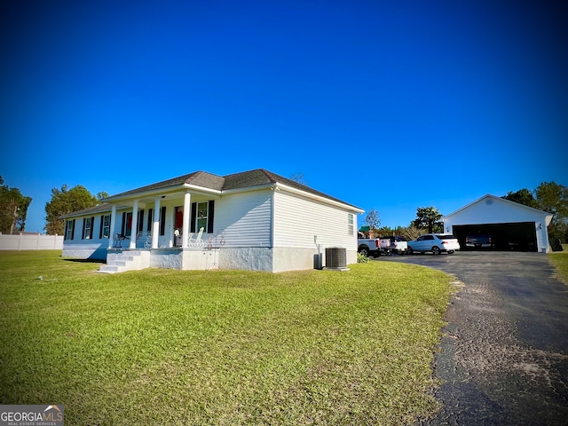 view of home's exterior featuring central air condition unit, a porch, an outbuilding, a yard, and a garage