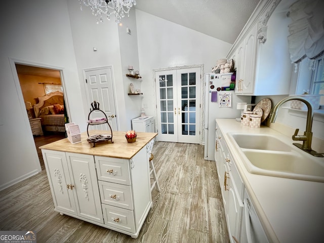 kitchen with french doors, white cabinets, a kitchen island, and sink