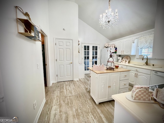 kitchen with white cabinetry, sink, hanging light fixtures, light hardwood / wood-style flooring, and white appliances