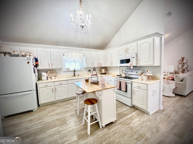 kitchen featuring white cabinets, a kitchen island, white appliances, and sink