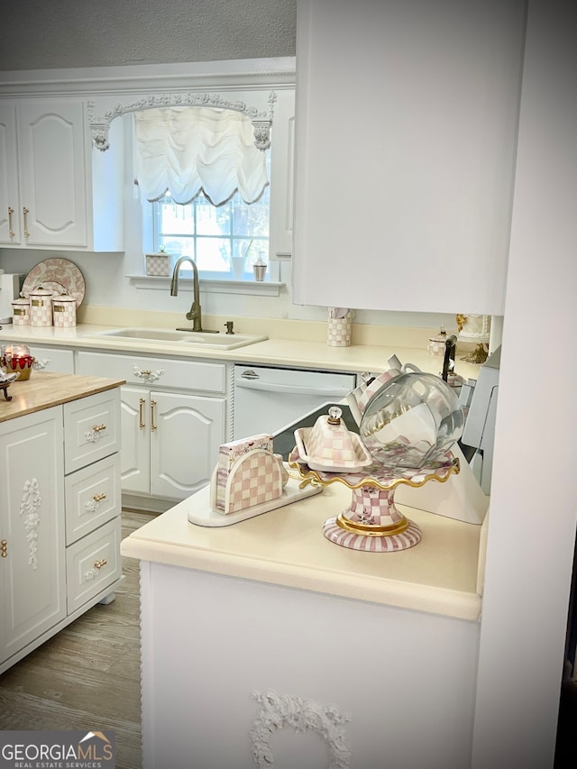 kitchen with white cabinets, wood-type flooring, dishwasher, and sink