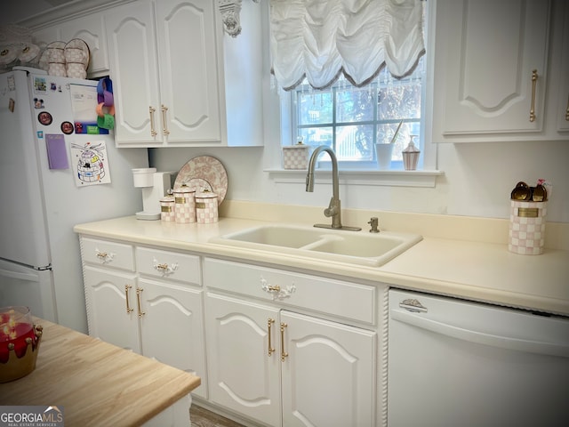 kitchen with white appliances, white cabinetry, and sink